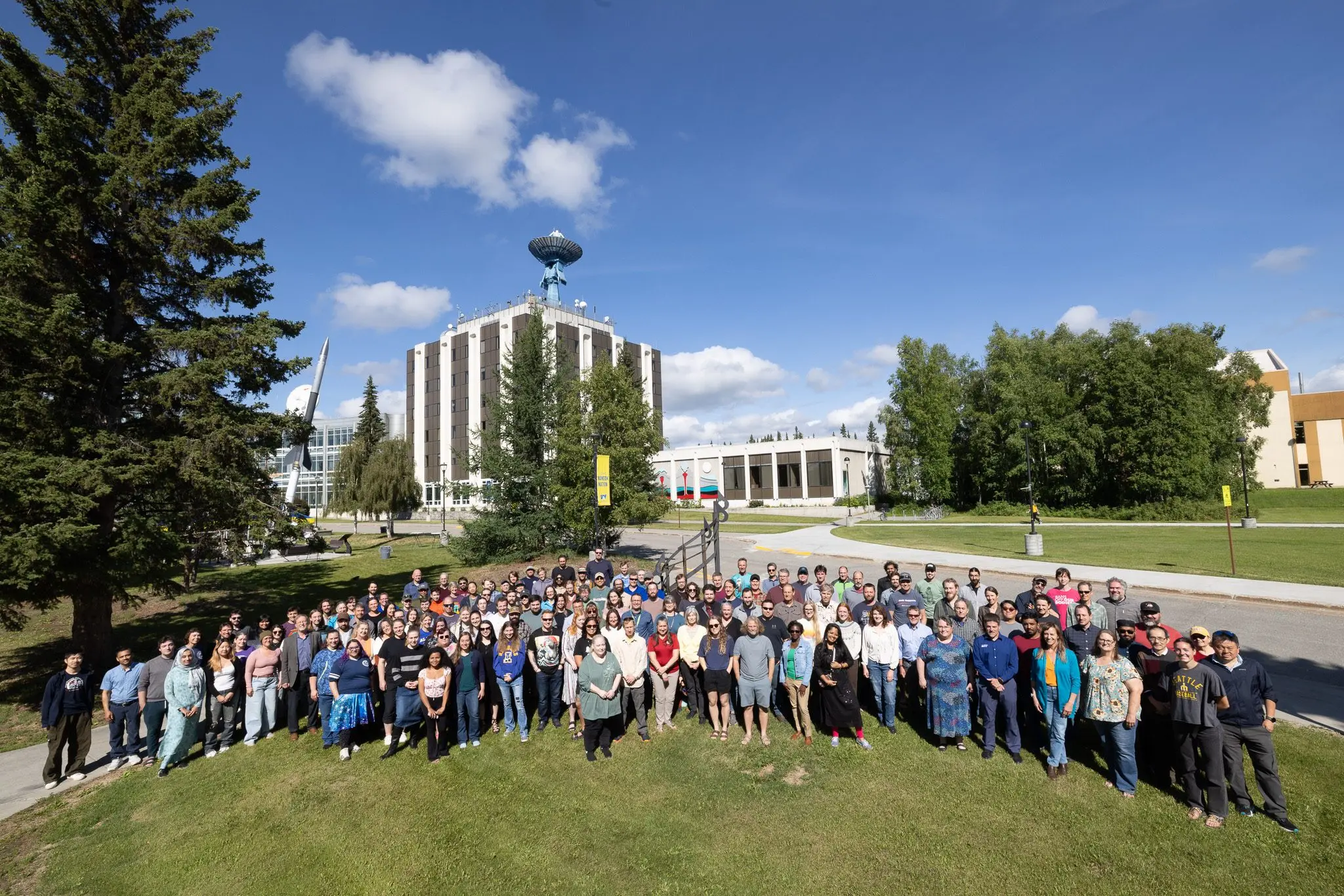Geophysical Institute faculty, staff and student researchers gather in 2025 for a group photo with the institute’s antenna-topped home building in the background. Photo by Bryan Whitten