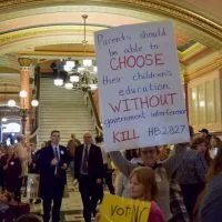 A woman holds a sign^ which is just one of the many signs held by the thousands of people who gathered in the Statehouse on Wednesday to oppose a bill relating to homeschoolers. (Capitol News Illinois photo by Jade Aubrey)