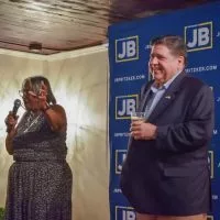 Gov. JB Pritzker holds a branded craft “JBeer” on stage at a Springfield campaign kickoff event alongside local state Sen. Doris Turner. (Capitol News Illinois photo by Jade Aubrey)