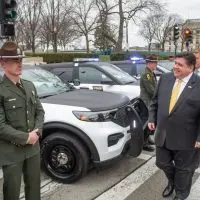 Gov. JB Pritzker passes in front of a row of Illinois State Police vehicles during a ceremony outside the Illinois Capitol in Springfield on March 30^ 2022. (Capitol News Illinois photo by Jerry Nowicki)