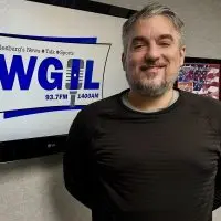 Galesburg Mayor Peter Schwartzman smiling in front of WGIL sign during radio interview