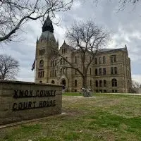 Knox County Courthouse sign in foreground with the historic stone courthouse building behind it in Galesburg^ Illinois