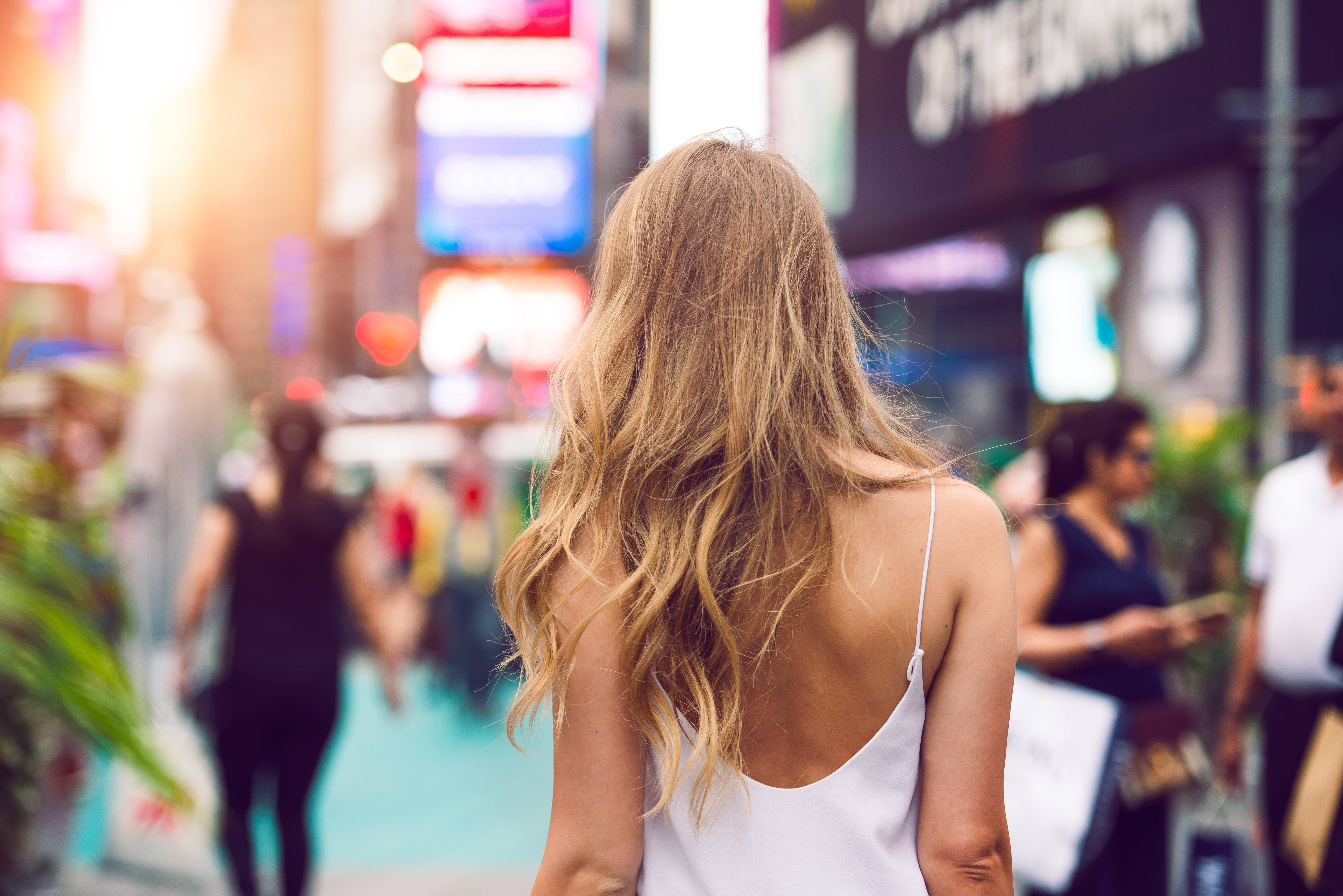 stylishblondewomanwalkingoutdoorsinsummercitystreetat