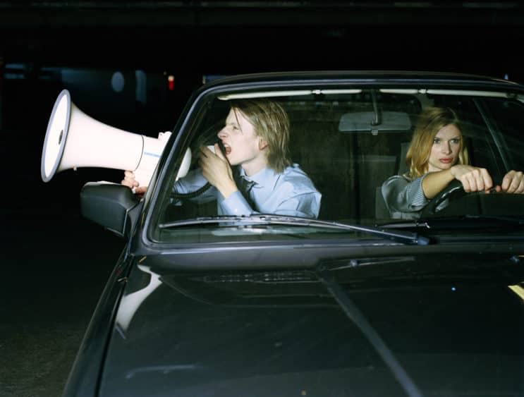 man-and-woman-in-car-man-using-megaphone-through-open-window