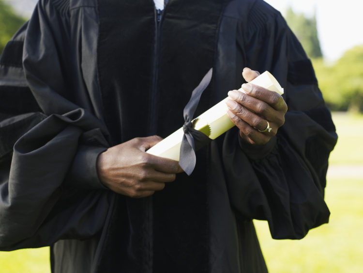 mature-woman-in-graduation-gown-holding-diploma-mid-section