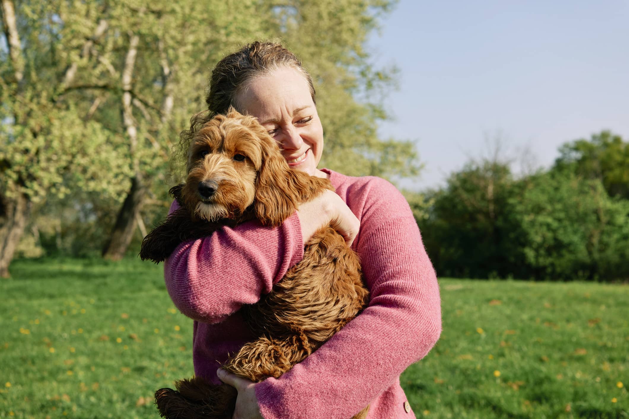 woman-cuddling-her-dog-in-a-field