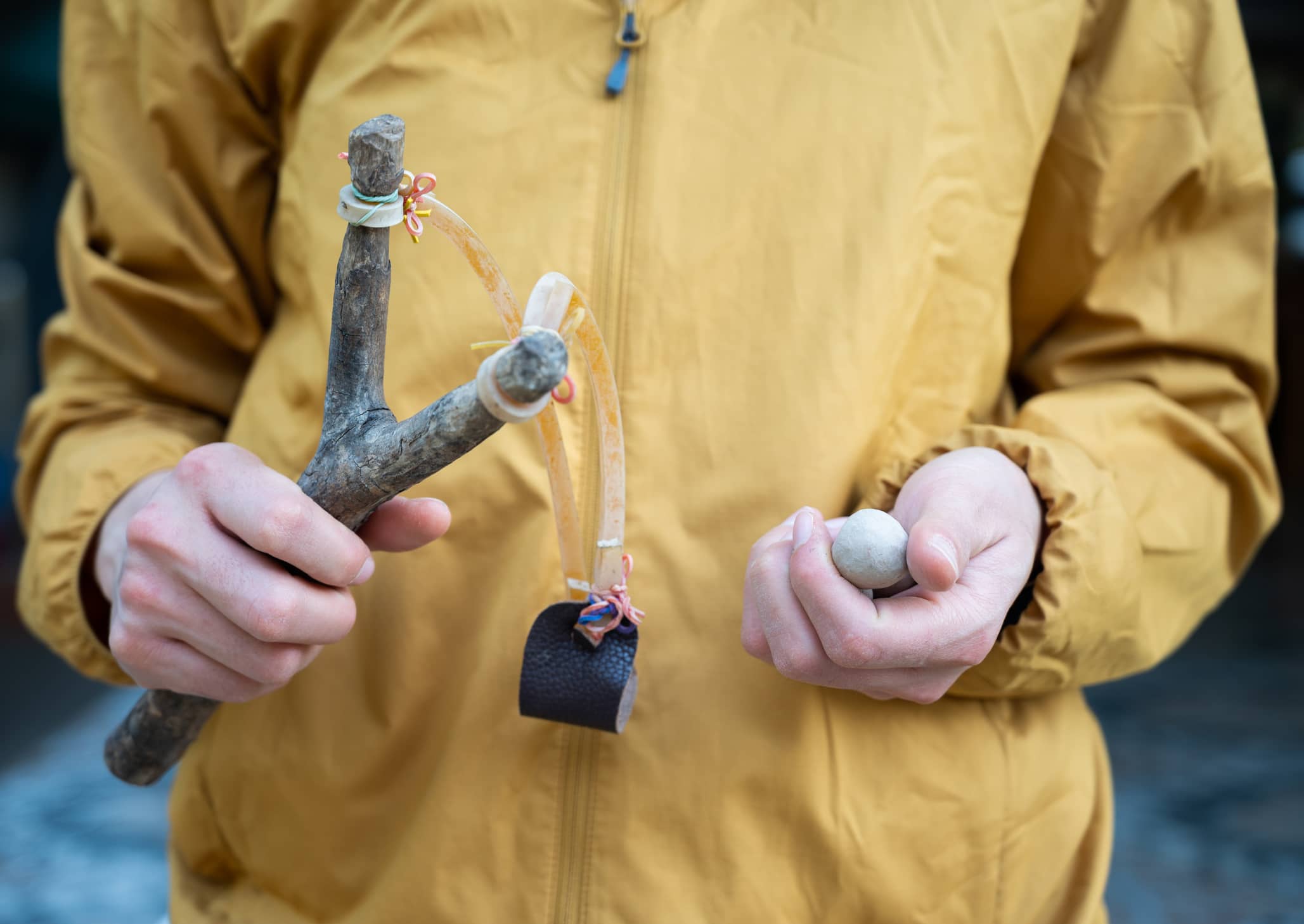 cropped-shot-of-woman-holding-a-wood-slingshot-with-clay-bullet-in-her-hands-a-slingshot-works-like-a-small-catapult-with-rubber-strips-holding-a-stone-or-other-projectile-sits