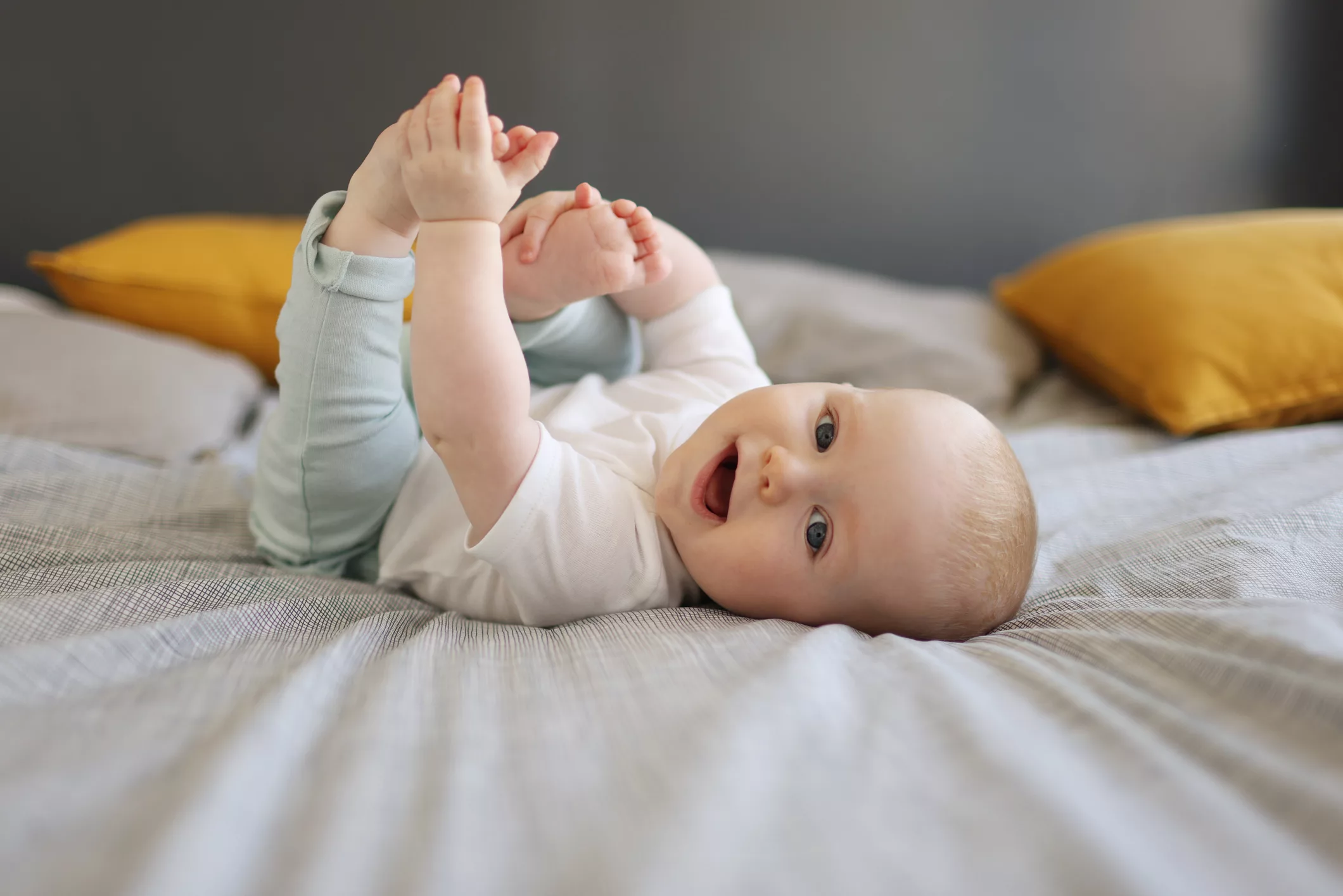 a-6-month-old-baby-boy-smiling-laying-on-a-bed