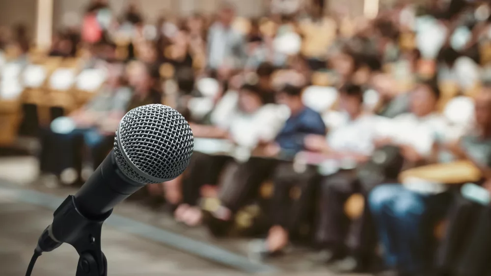 microphone-over-the-abstract-blurred-photo-of-conference-hall-or-seminar-room-with-attendee-background