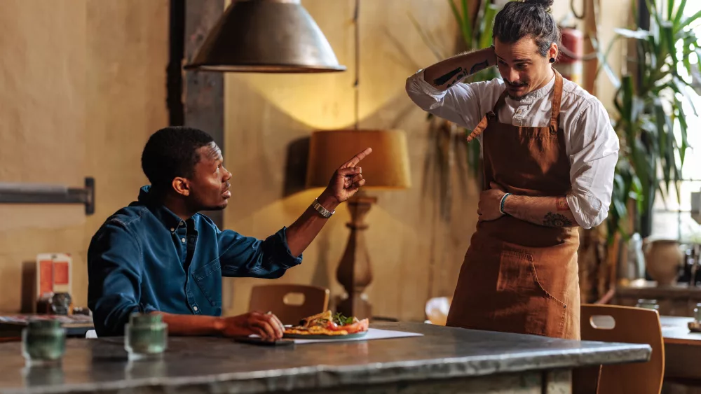 angry-african-american-man-complaining-over-dish-to-ashamed-hispanic-waiter