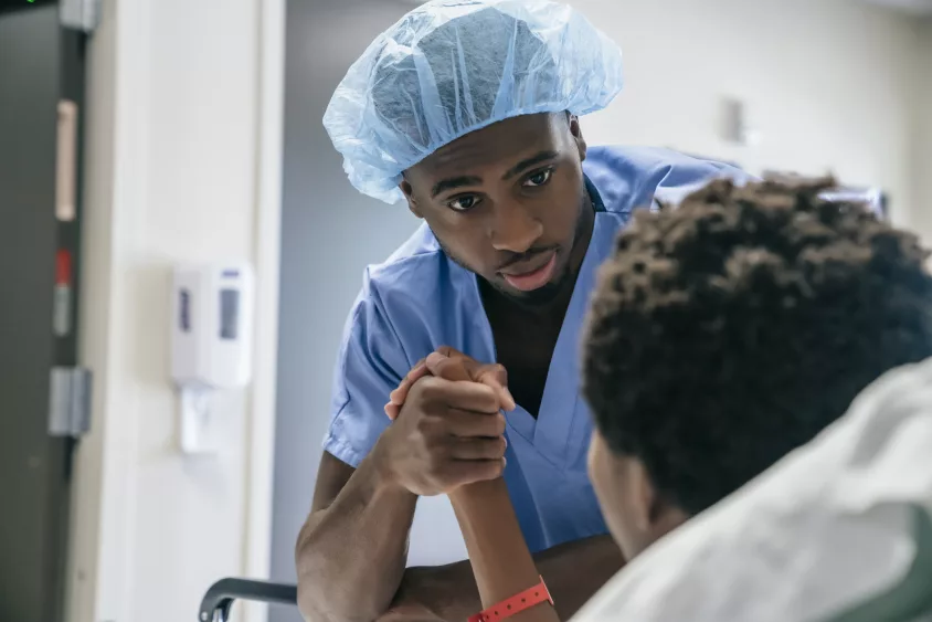 black-doctor-holding-hand-of-boy-in-hospital-bed