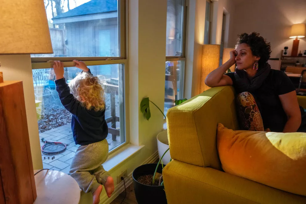 SPRING, TEXAS - DECEMBER 14: Sihem Fekih-Soibinet, 39, watches over her son Isaac Soibinet, 1, as he looks out the window of their home on Thursday, Dec. 14, 2023, in Spring. Corentin and Sihem have been juggling working remotely from home and caring for their 1 year old son after his daycare recently closed abruptly. (Raquel Natalicchio/Houston Chronicle via Getty Images)