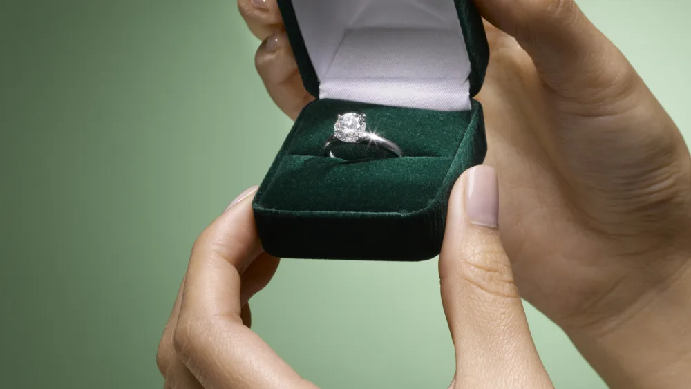 womans-hands-holding-diamond-ring-in-box-close-up
