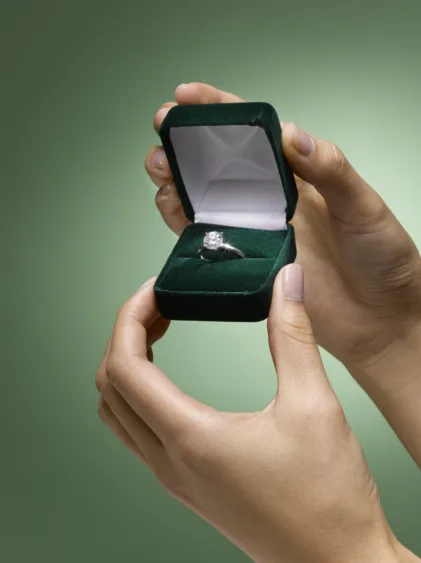 womans-hands-holding-diamond-ring-in-box-close-up