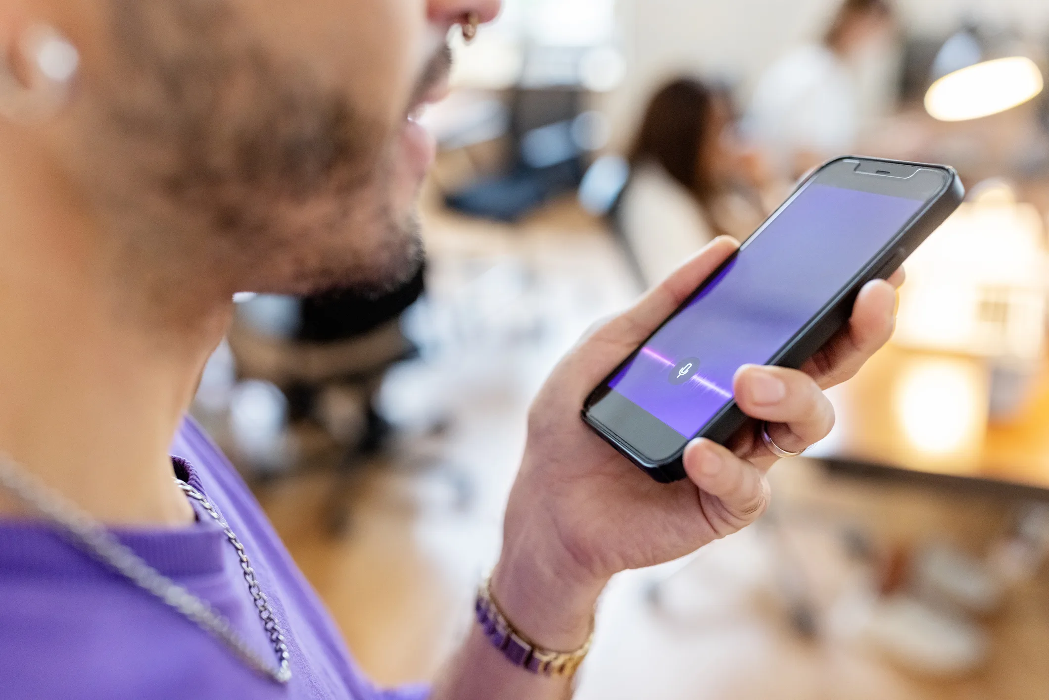 close-up-of-man-recording-voice-message-on-cellphone-at-office