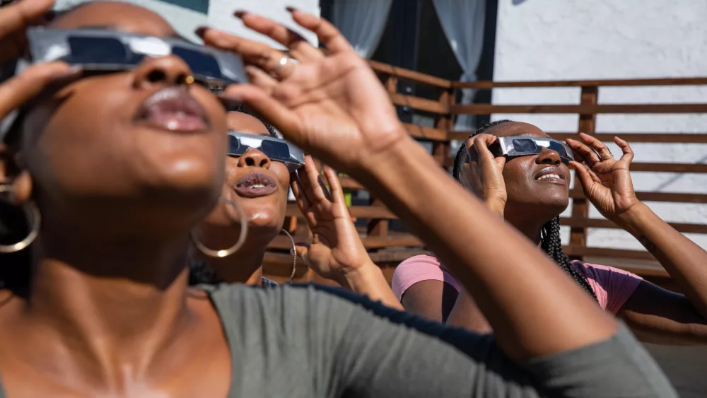 women-friends-at-home-enjoying-solar-eclipse-looking-at-the-sun-with-eclipse-sunglasses