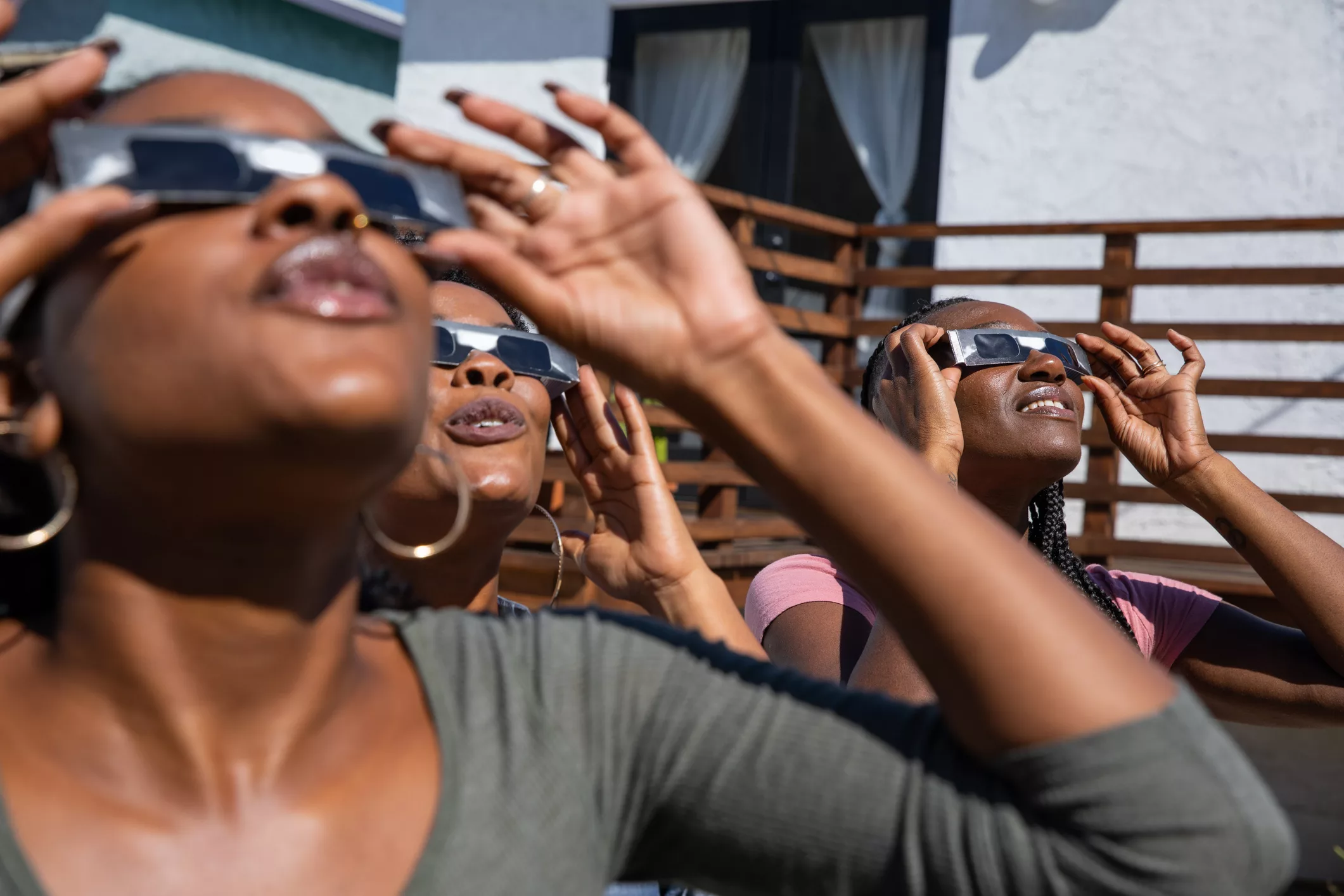 women-friends-at-home-enjoying-solar-eclipse-looking-at-the-sun-with-eclipse-sunglasses