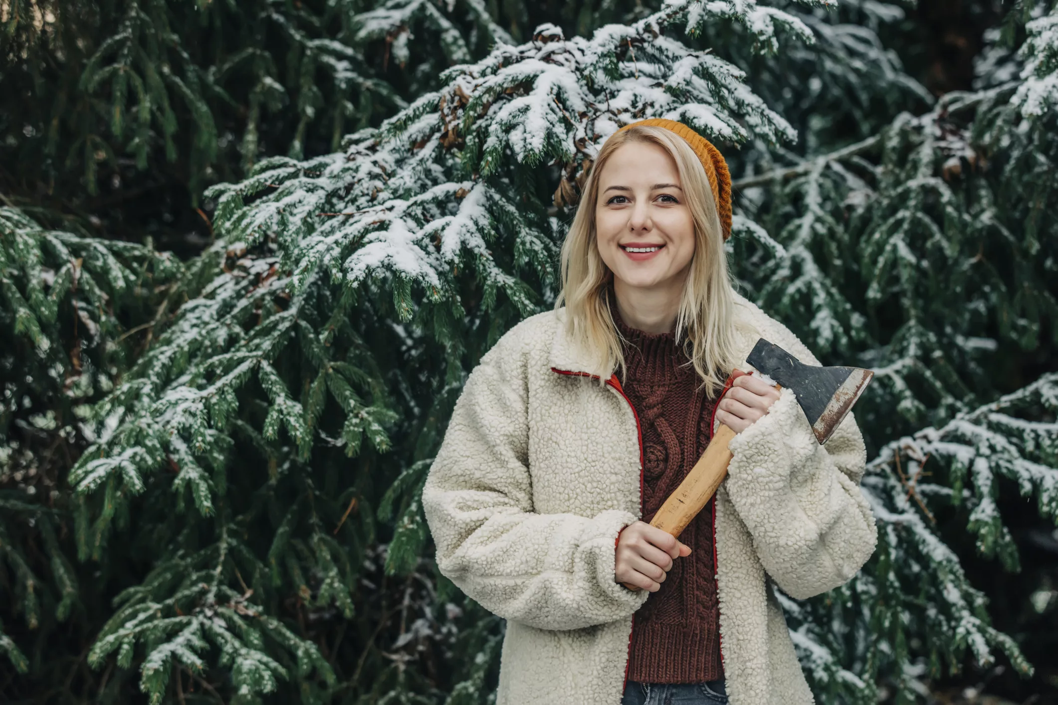 smiling-woman-with-blond-hair-holding-axe-in-front-of-christmas-tree