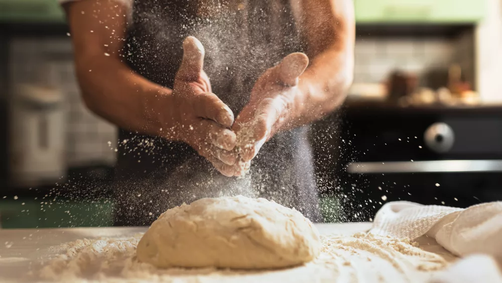 chefs-hands-spraying-flour-over-the-dough