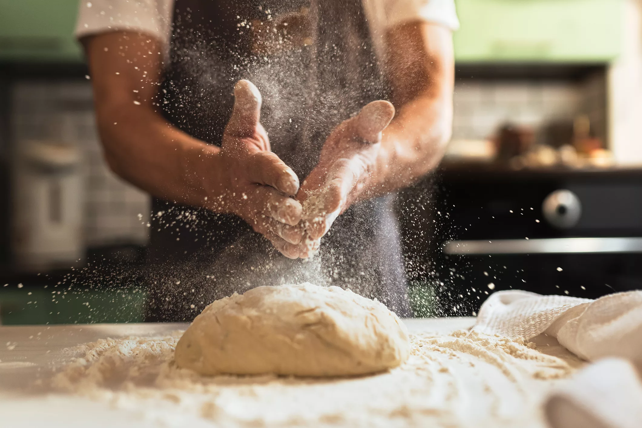 chefs-hands-spraying-flour-over-the-dough