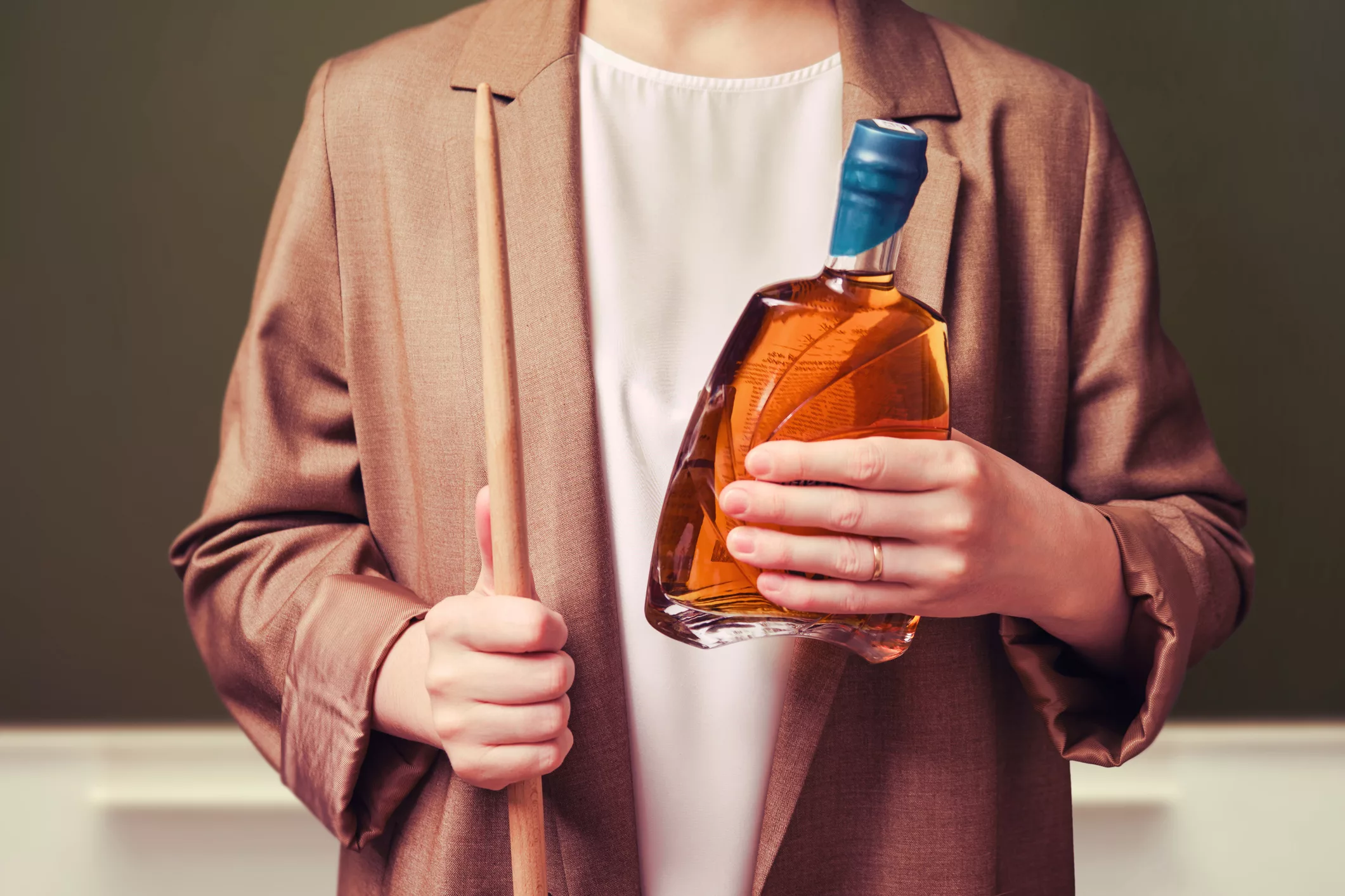 woman-teacher-holding-bottle-of-alcohol-on-school-blackboard-in-the-classroom-close-up