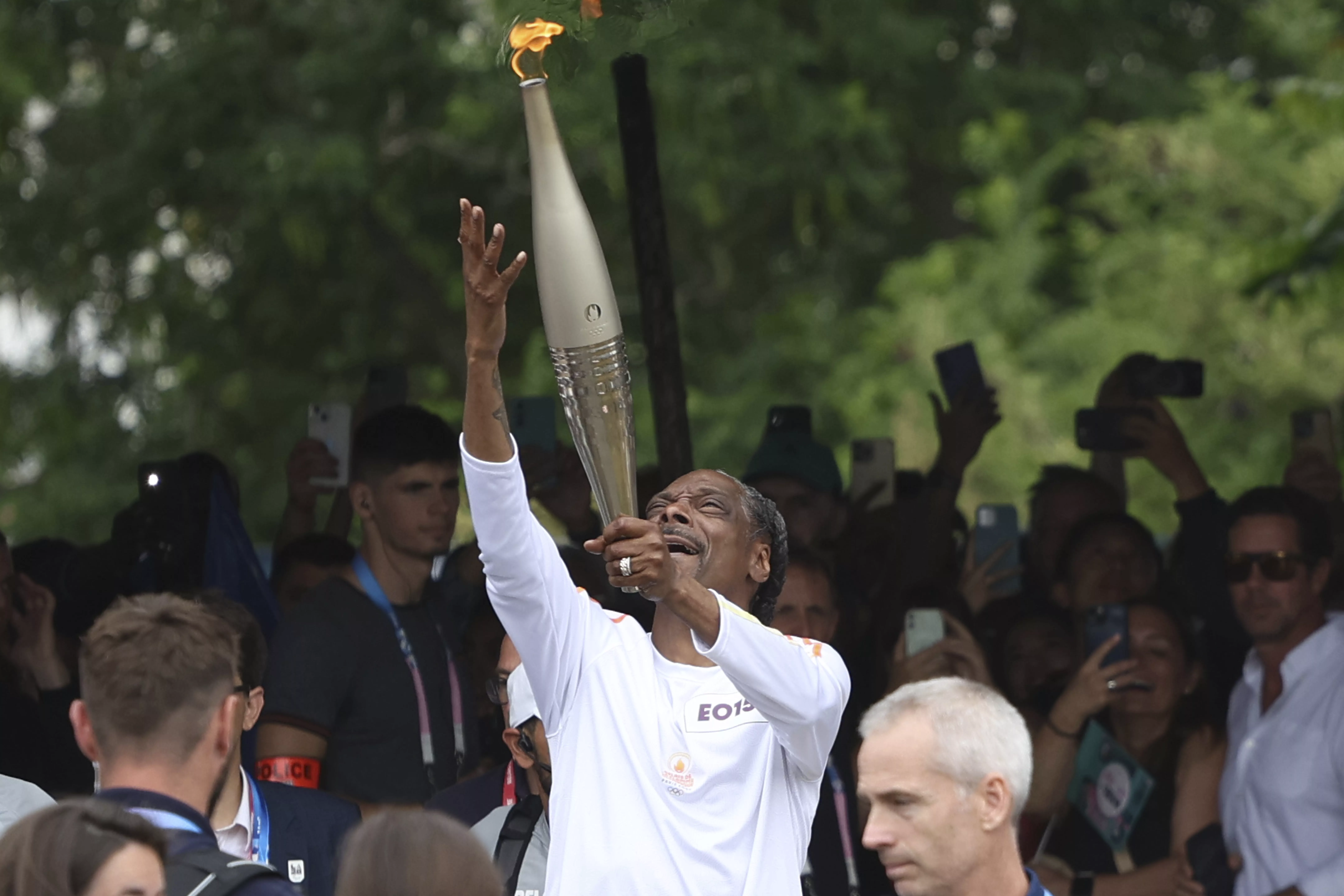 Snoop Dogg carries the Olympic torch at the 2024 Summer Olympics, Friday, July 26, 2024, in Saint-Denis, outside Paris, France. (AP Photo/Aurelien Morissard)