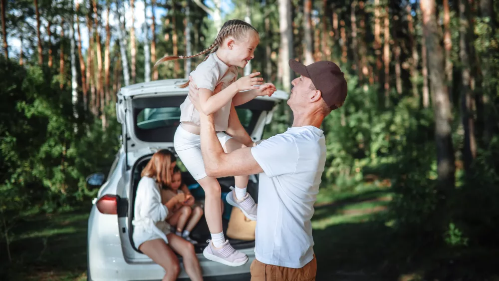 authentic-family-journey-mom-dad-two-children-in-car-in-woodland-road-trip-adventure-with-kids-nature-retreat