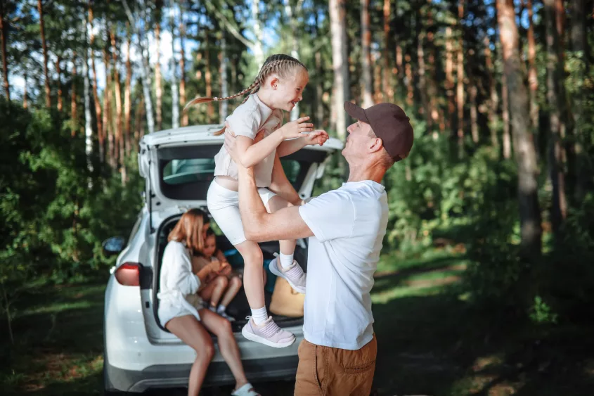 authentic-family-journey-mom-dad-two-children-in-car-in-woodland-road-trip-adventure-with-kids-nature-retreat