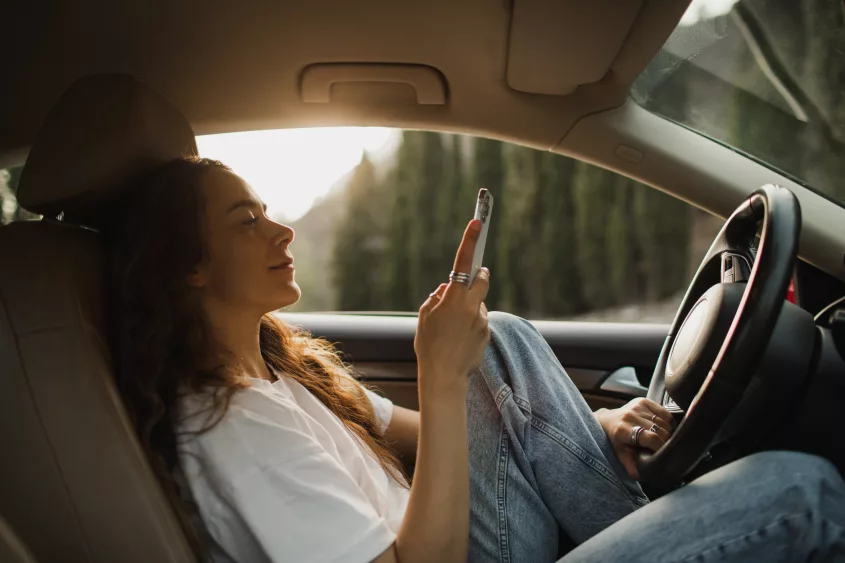 woman-relaxing-in-car-at-sunset-and-wasting-time-on-social-media-in-smartphone