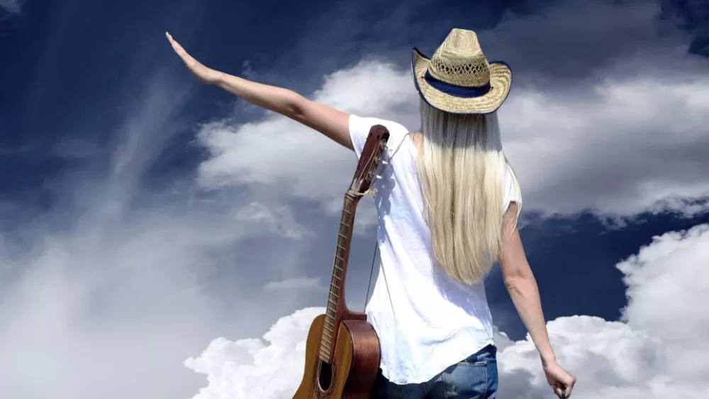 Young woman with guitar on the road and her vintage baggage