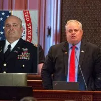 Rep. Dan Swanson^ R-Alpha^ is pictured on the Illinois House floor alongside a picture of him in military uniform.