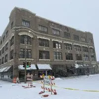 Wide view of Weinberg Arcade building in downtown Galesburg with caution tape^ road closed sign^ and scattered bricks after facade collapse.
