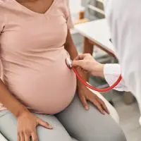 Doctor listens to a pregnant woman’s abdomen using a stethoscope. (Photo Credit: Krakenimages.com^ adobe stock)