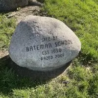 A stone marker at the former site of Bateman School in Galesburg^ Illinois^ reading "Site of Bateman School^ Est. 1930^ Razed 2001."