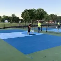 Workers applying blue playing surface to new pickleball courts at Rotary Park in Galesburg^ Illinois^ June 2026