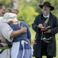 A reenactor reads from a book to a group in period dress at Galesburg Heritage Days