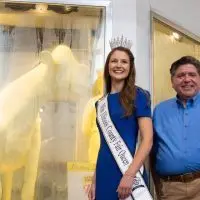 Illinois State Fair Quen Krista Phillips and Gov. JB Pritzker pose with the 2026 Illinois State Fair butter cow. (Capitol News Illinois photo by Jerry Nowicki)