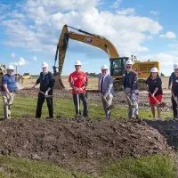 Nine people in hard hats holding shovels at the Carl Sandburg College Charger Center groundbreaking ceremony