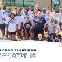 Group of runners and walkers wearing Team Blue shirts for the Coach Rodney Blue Charitable Run