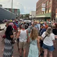 ALT TEXT: Crowd gathered on brick-paved Seminary Street during a First Fridays event with a band performing