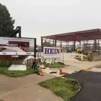 A sign showing a rendering of the National Railroad Hall of Fame stands in front of the red steel frame of the building under construction in Galesburg.