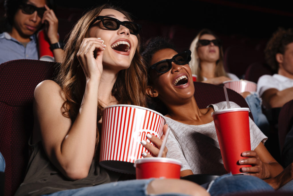 cheerful-friends-sitting-in-cinema-watch-film