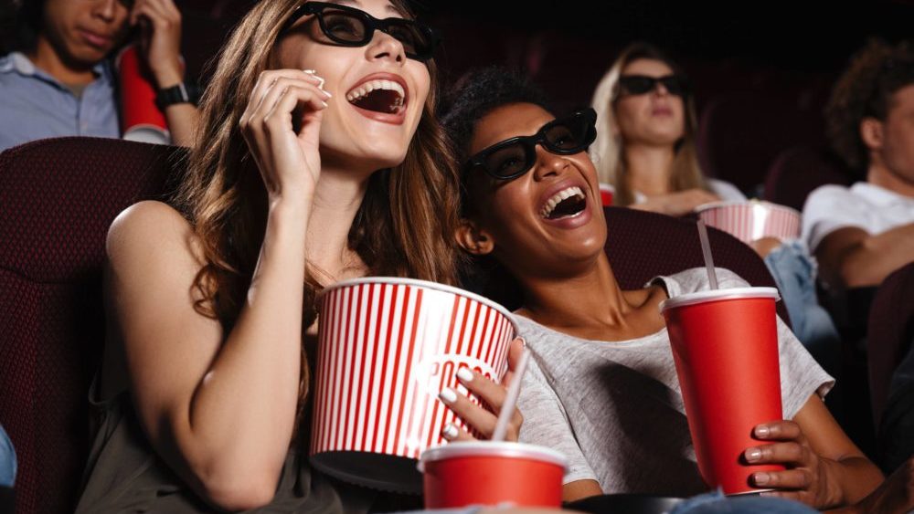 cheerful-friends-sitting-in-cinema-watch-film