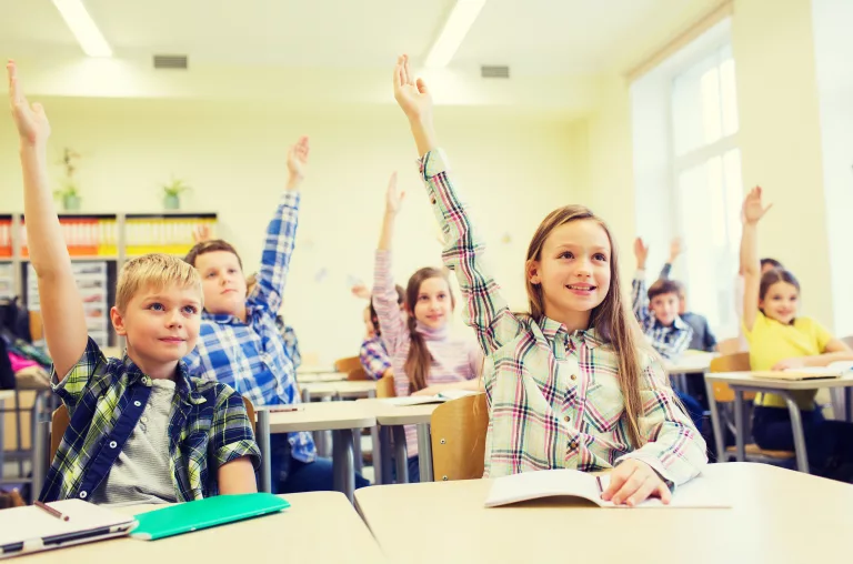 group-of-school-kids-raising-hands-in-classroom-2