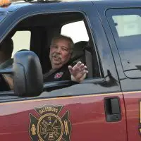 Tom “Baughie” Baughman smiles and waves from the window of a Galesburg Fire Department rescue truck. Courtesy photo by Bill Dickerson.
