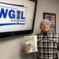 Derek Peters holding Explore Galesburg coloring book cover at WGIL studios