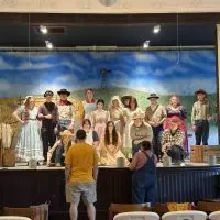 Youth cast in costume on stage during a rehearsal at Ransom Memorial Library Hall in Altona