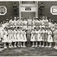 Black and white photo of Cottage School of Nursing students and staff in uniform outside the Zeller Building