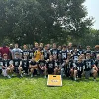 Galesburg Silver Streaks football players and coaches posing together on a grass field