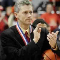 ALT TEXT: Thom Sigel wearing a medal and applauding while holding a basketball